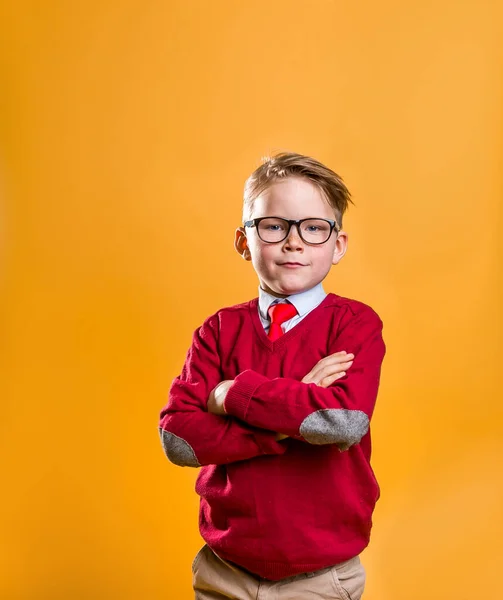 Ritratto di ragazzo di sette anni carino e sicuro di sé su sfondo giallo. Allievo in uniforme da business school e occhiali. Il concetto di educazione, successo, motivazione, vincitore, genio, innovazione — Foto Stock