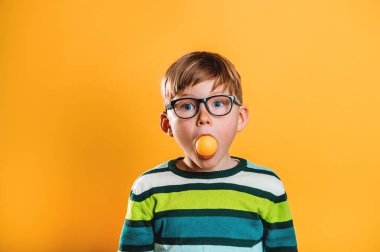 Ağzında ampul olan komik çocuk. Büyük gözlüklü küçük dahi eğitime hazır. Hayal gücü, fikir ve başarı. Gözlüklü çocuk eğitime hazır. Okula geri dön..