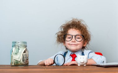 Takım elbiseli ve paralı gözlüklü küçük patron portresi. Ofisteki iş adamı. Çocuk para tutuyor. Genç iş adamı ya da kız. Çocuk gelecekteki iş adamı olmak istiyor. Gelecekte eğitim, meslek.