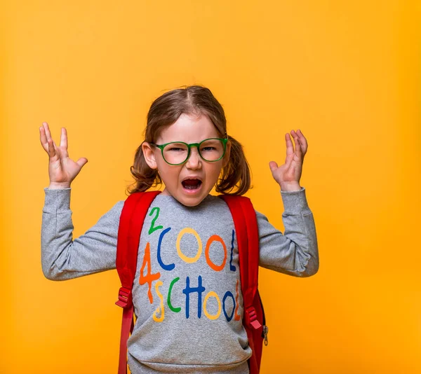 Pupil girl is angry very much. Crazy and mad shouting kid isolated on yellow background. and yelling with aggressive expression and arms raised. Frustration concept