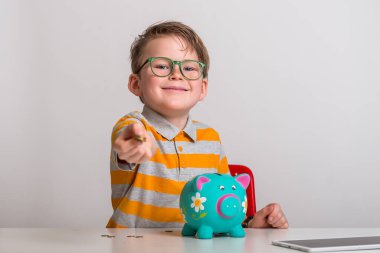 Çocuk kumbaraya bozuk para sokuyor. Para kutusuna para koyan çocuk portresi. Çocuk kumbaraya para koyarken para biriktirir.
