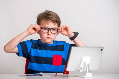 Dizüstü bilgisayarda çalışan gözlüklü zeki çocuk. Gözlüklü çocuk ödev yapıyor.