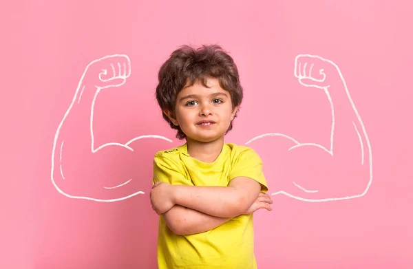 Сильный маленький мальчик с бицепсными мышцами. Концепция силы, уверенности или защиты от издевательств. Детский сад или школьник. Сильный мальчик — стоковое фото