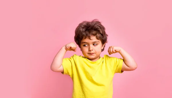 Lustigt starkt barn som visar musklerna. Ett litet pojkmaktskoncept. Superhjälte koncept för dagis barn. Framgång, motivation, utbildning. Tillbaka till skolan. Pojke affärsman isolerad på rosa. — Stockfoto