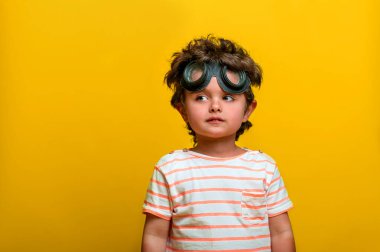 Funny little kid boy wear pilot hat and glasses isolated on yellow background. Kindergarten child playing with airplane and flying, Start up, freedom, idea, school, innovation