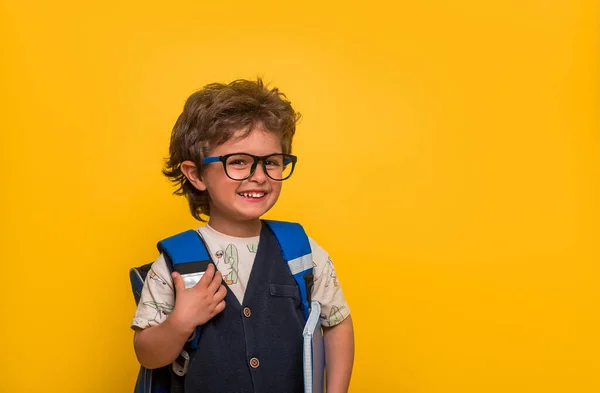 小男孩，带着书和书包被隔离在黄色的纸墙上。快乐的微笑的孩子回到学校，幼儿园。成功，动力，赢家，天才的概念。很有趣的孩子梦想成为超级英雄 — 图库照片