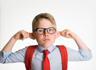 Okul üniformalı, kulaklarını çeken ve beyaz arka planda izole edilmiş dilini gösteren komik zeki çocuk. Öğrenci maymun suratı yapıyor. Komik şapşal çocuk yüzünü buruşturuyor.