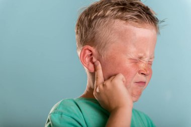Küçük okul çocuğu kulak ağrısından muzdarip. Kulaktan kulağa çocuk hareketi. Çocuk gözlerini kapar ve acı çeker. Çocuk sağlığı