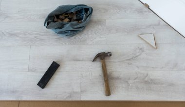 Yeni beyaz kaplama takılıyor. Ahşap zeminde işçi aletleri. Çekiç