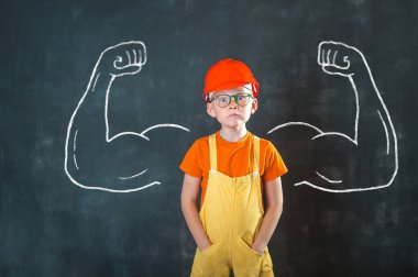 Güvenli kırmızı kasklı çocuk portresi ve büyük kaslı müteahhit üniforması. Başarı, yaratıcı ve yenilikçi iş konsepti. Okullu çocuk inşaatçı olmayı hayal ediyor. Çocuk mesleği. Akıllı çocuk.