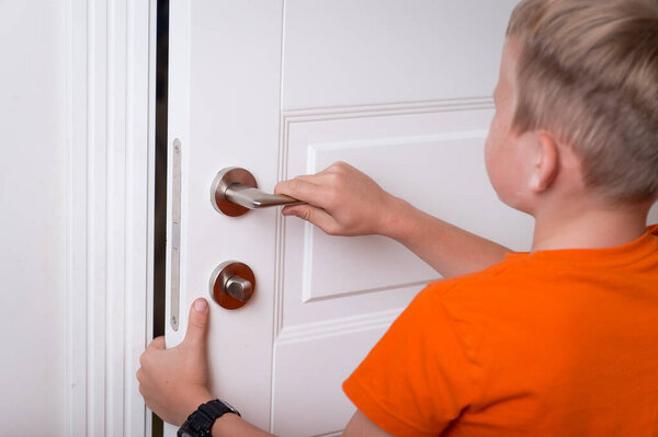 Школьник ткнул пальцами в дверь. Приватная территория для ребенка. Мальчики руки торчат из закрытой двери. Предотвращение детской опасности.