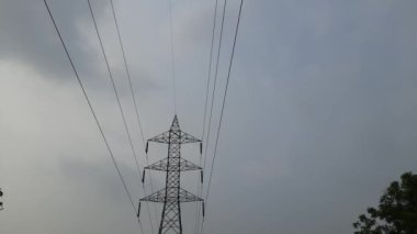 Yüksek voltaj direği ya da yüksek voltaj kulesi. Yüksek voltajlı iletim hatları ve elektrik kuleleri olan alanlar. Yüksek voltaj direği. Siyah bulutlu arka planda yüksek voltaj kulesi.