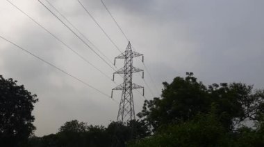 Yüksek voltaj direği ya da yüksek voltaj kulesi. Yüksek voltajlı iletim hatları ve elektrik kuleleri olan alanlar. Yüksek voltaj direği. Siyah bulutlu arka planda yüksek voltaj kulesi.