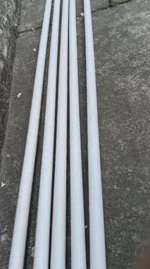 Elektrikli PVC borular. Beyaz, sert plastik borular eski, gri beton bir yüzeye, dokulu bir duvarın yanına konur. Bu borular elektrik kabloları için kullanılıyor..