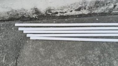 Elektrikli PVC borular. Beyaz, sert plastik borular eski, gri beton bir yüzeye, dokulu bir duvarın yanına konur. Bu borular elektrik kabloları için kullanılıyor..