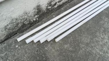 Elektrikli PVC borular. Beyaz, sert plastik borular eski, gri beton bir yüzeye, dokulu bir duvarın yanına konur. Bu borular elektrik kabloları için kullanılıyor..