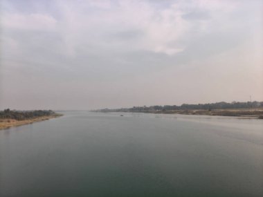 Uzaktaki geniş bir nehirde küçük bir teknede iki kişi balık tutuyor. İçinde iki kişi olan küçük bir ahşap tekne bulutlu, puslu bir gökyüzünün altında geniş ve sakin bir nehirde yüzüyor. Sahne huzurlu ve büyüleyici bir akşam sükuneti hissi uyandırıyor..