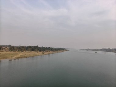 Uzaktaki geniş bir nehirde küçük bir teknede iki kişi balık tutuyor. İçinde iki kişi olan küçük bir ahşap tekne bulutlu, puslu bir gökyüzünün altında geniş ve sakin bir nehirde yüzüyor. Sahne huzurlu ve büyüleyici bir akşam sükuneti hissi uyandırıyor..