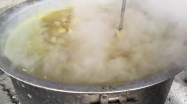 Büyük metal bir tencere khichdi pişiriyor. Kömür ocağında kırsal bir ortamda pişirilen geleneksel, yaygın bir yemek. Pirinç, nabız, sebze ve baharat karıştırılarak yapılır. Geleneksel Hint yemekleri.