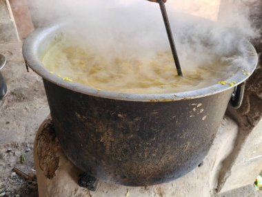 Büyük metal bir tencere khichdi pişiriyor. Kömür ocağında kırsal bir ortamda pişirilen geleneksel, yaygın bir yemek. Pirinç, nabız, sebze ve baharat karıştırılarak yapılır. Geleneksel Hint yemekleri.