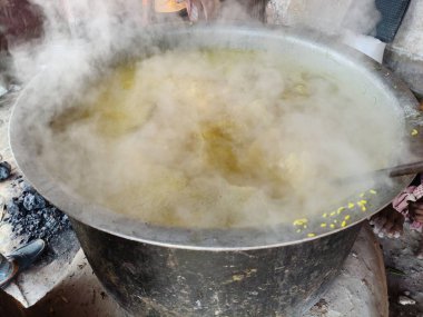 Büyük metal bir tencere khichdi pişiriyor. Kömür ocağında kırsal bir ortamda pişirilen geleneksel, yaygın bir yemek. Pirinç, nabız, sebze ve baharat karıştırılarak yapılır. Geleneksel Hint yemekleri.