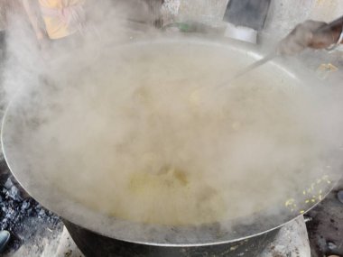 Büyük metal bir tencere khichdi pişiriyor. Kömür ocağında kırsal bir ortamda pişirilen geleneksel, yaygın bir yemek. Pirinç, nabız, sebze ve baharat karıştırılarak yapılır. Geleneksel Hint yemekleri.