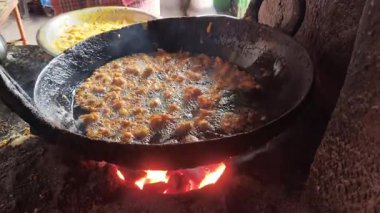 Soğan pakoraları büyük bir demir tavada kızartılıyor. Bu otantik Hint sokak yemekleri geleneksel kil sobanın üzerinde, yanan kömürlerin üzerinde hazırlanıyor. Hint yemekleri..