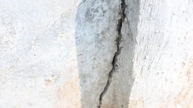 Çimento duvarında bir çatlak ortaya çıktı. Bu çatlak, yapının hafif toprak üzerine inşa edildiği, yağmur mevsiminde toprak aşındığı ve duvarın çatlamasına neden olduğu için meydana gelir. Bu da inşaat alanında hasar olduğunu gösterir..