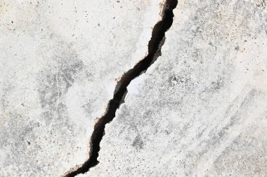 Çimento duvarında bir çatlak ortaya çıktı. Bu çatlak, yapının hafif toprak üzerine inşa edildiği, yağmur mevsiminde toprak aşındığı ve duvarın çatlamasına neden olduğu için meydana gelir. Bu da inşaat alanında hasar olduğunu gösterir..