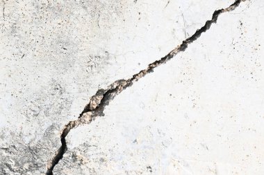 Çimento duvarında bir çatlak ortaya çıktı. Bu çatlak, yapının hafif toprak üzerine inşa edildiği, yağmur mevsiminde toprak aşındığı ve duvarın çatlamasına neden olduğu için meydana gelir. Bu da inşaat alanında hasar olduğunu gösterir..