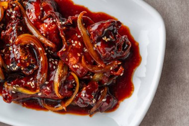 Ayam goreng mentega ya da soya soslu kızarmış tavuk, tereyağı ve soğan beyaz tabakta servis edilir..