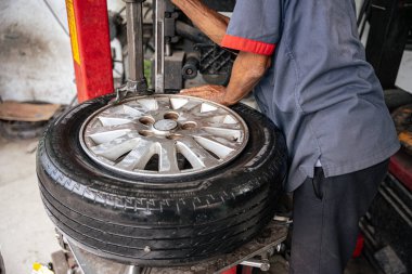 Servis atölyesinde araba tamircisinin lastiği çiviyle patlamış. Lastik dükkanında lastik değiştiren bir tamircinin yakın çekimi..