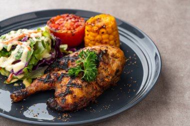 Sarımsak, soya, zencefil ve bal sosunda pişirilmiş yarım tavuk. Fırında mısır, salata ve domates tabağı.. 