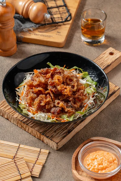 Siyah tabakta mayonez kaplı gevrek et fileto parçaları.