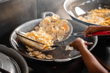 Balado 'yu boşaltma işlemi, Batı Sumatra' dan Baharatlı Atıştırmalıklar. Melinjo krakerlerinden yapılmış, çıtır çıtır, tatlı ve baharatlı..