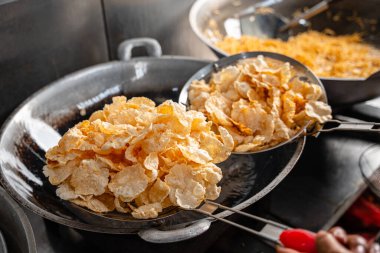 Balado 'yu boşaltma işlemi, Batı Sumatra' dan Baharatlı Atıştırmalıklar. Melinjo krakerlerinden yapılmış, çıtır çıtır, tatlı ve baharatlı..