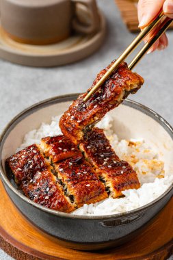 Unagi donburi tipi büyük bir kase dolusu buharda pişmiş beyaz pirinç ve üzeri de kabayaki olarak bilinen ızgara yılan balığı filetosu ile kaplı, Teriyaki 'ye benzer..