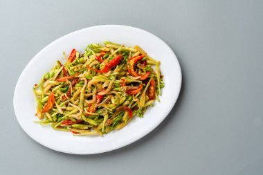 Tumis Bunga Pepaya ikan teri Endonezya 'nın geleneksel yemeğidir. Kızart Papaya 'nın tomurcuklarını ve çiçeklerini kızarmış ançüezle Beyaz tabakta servis edilir ve gri arka planda izole edilir.