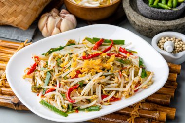 Tumis Tauge ikan asin ya da Salted Bean Sprout Endonezya 'nın geleneksel yemeklerinden biridir. Tabakta servis edilen tuzlu balıkla pişirilmiş sotelenmiş fasulye filizi ve izole edilmiş gri arka plan..