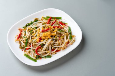 Tumis Tauge ikan asin ya da Salted Bean Sprout Endonezya 'nın geleneksel yemeklerinden biridir. Tabakta servis edilen tuzlu balıkla pişirilmiş sotelenmiş fasulye filizi ve izole edilmiş gri arka plan..
