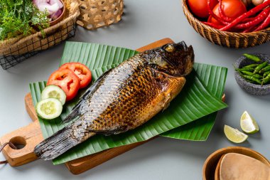 Izgara tilapia ya da muz yaprağında servis edilen ikan nila panggang. 