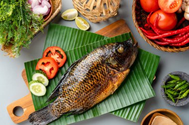 Izgara tilapia ya da muz yaprağında servis edilen ikan nila panggang. 