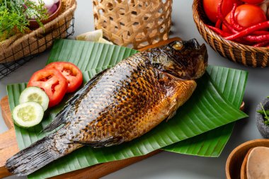 Izgara tilapia ya da muz yaprağında servis edilen ikan nila panggang. 