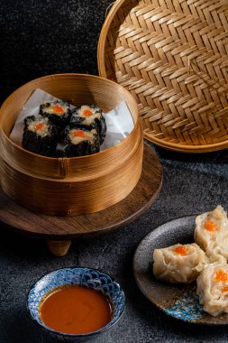 Bambu sepetinde çeşit çeşit Çin Dimsum 'u. Dimsum, Kanton halkının geleneksel olarak kahvaltı ve öğle yemeği için restoranlarda yediği küçük tabakların geniş bir yelpazesidir..