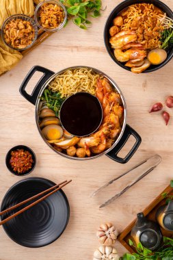 Hokkien mee veya karidesli erişte domuz yağına karıştırılır ve balık köftesi ve karides ile servis edilir..