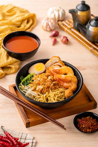 Hokkien mee veya karidesli erişte domuz yağına karıştırılır ve balık köftesi ve karides ile servis edilir..