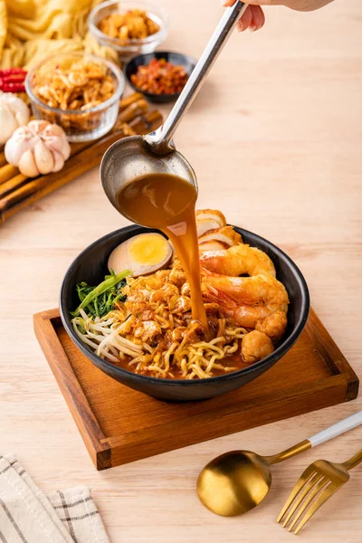 Hokkien mee veya karidesli erişte domuz yağına karıştırılır ve balık köftesi ve karides ile servis edilir..