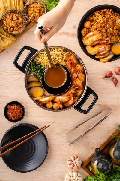 Hokkien mee veya karidesli erişte domuz yağına karıştırılır ve balık köftesi ve karides ile servis edilir..