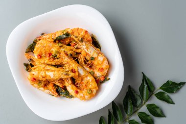 udang saus telur asin ya da beyaz tabakta servis edilen körili karidesli yumurtalı yumurta.