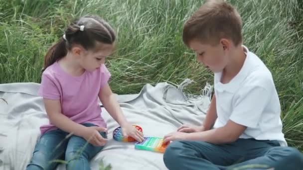 Dos niños están jugando nuevo juguete popular fidget popit y hoyuelo simple — Vídeo de stock